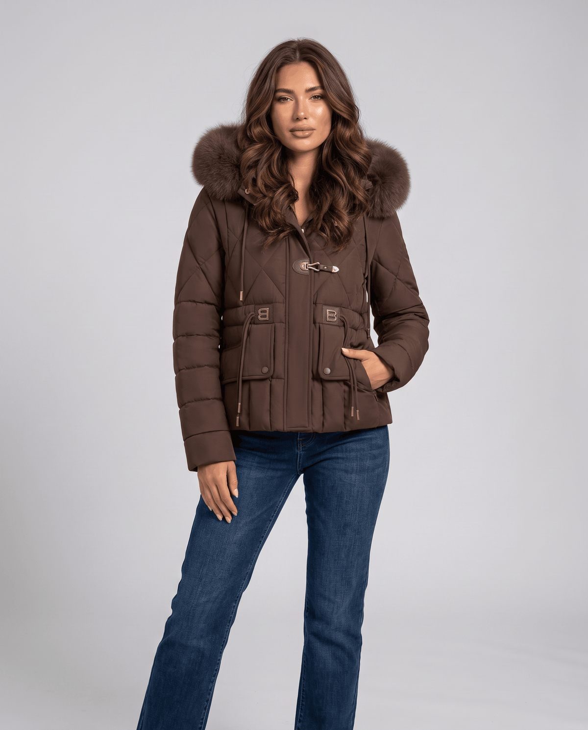 Model in brown quilted jacket with hands in pockets, styled with blue jeans