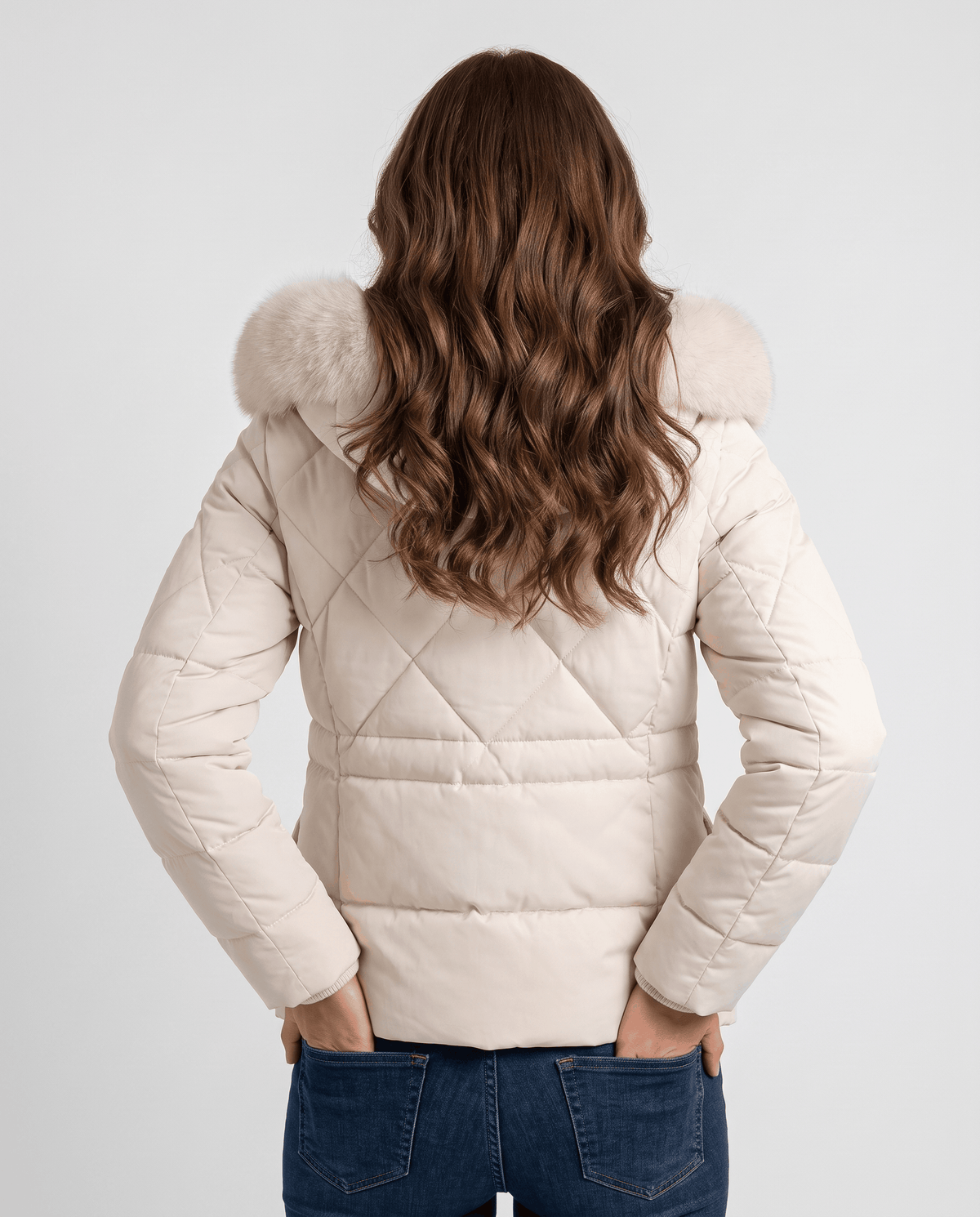 Back view of white quilted jacket with diamond panels, worn with jeans