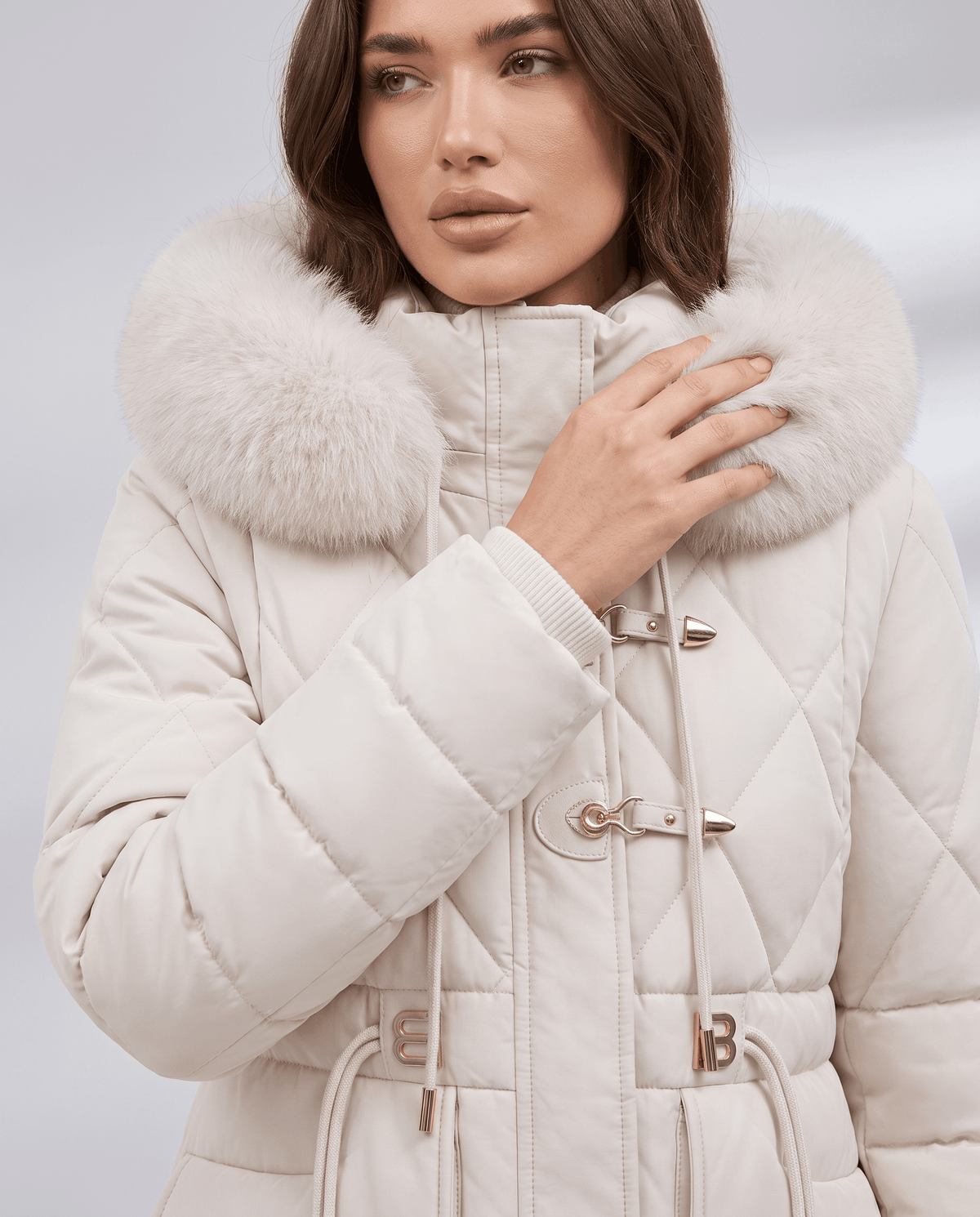 Close-up of white plush hood trim, hook clasps and quilted sleeve on model