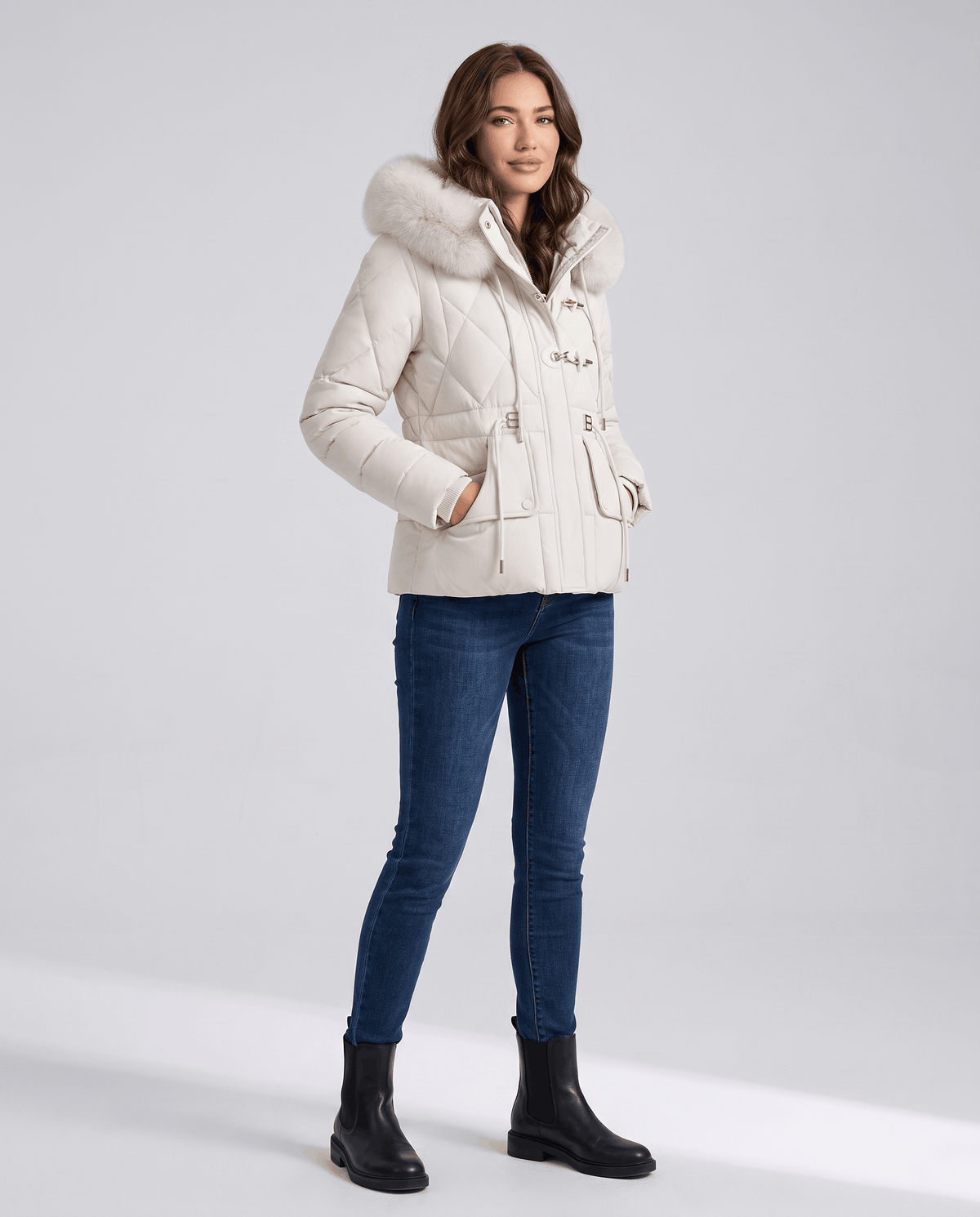 Side view of model in white quilted jacket with jeans and black boots