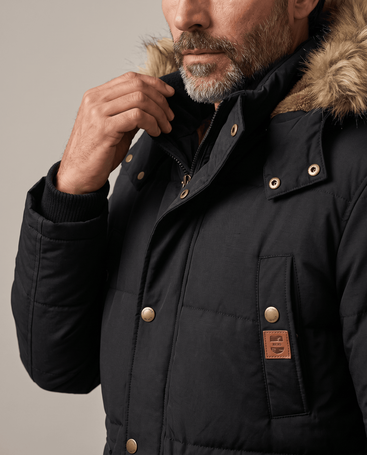 Close-up of black parka collar with snap buttons and small tan label on pocket