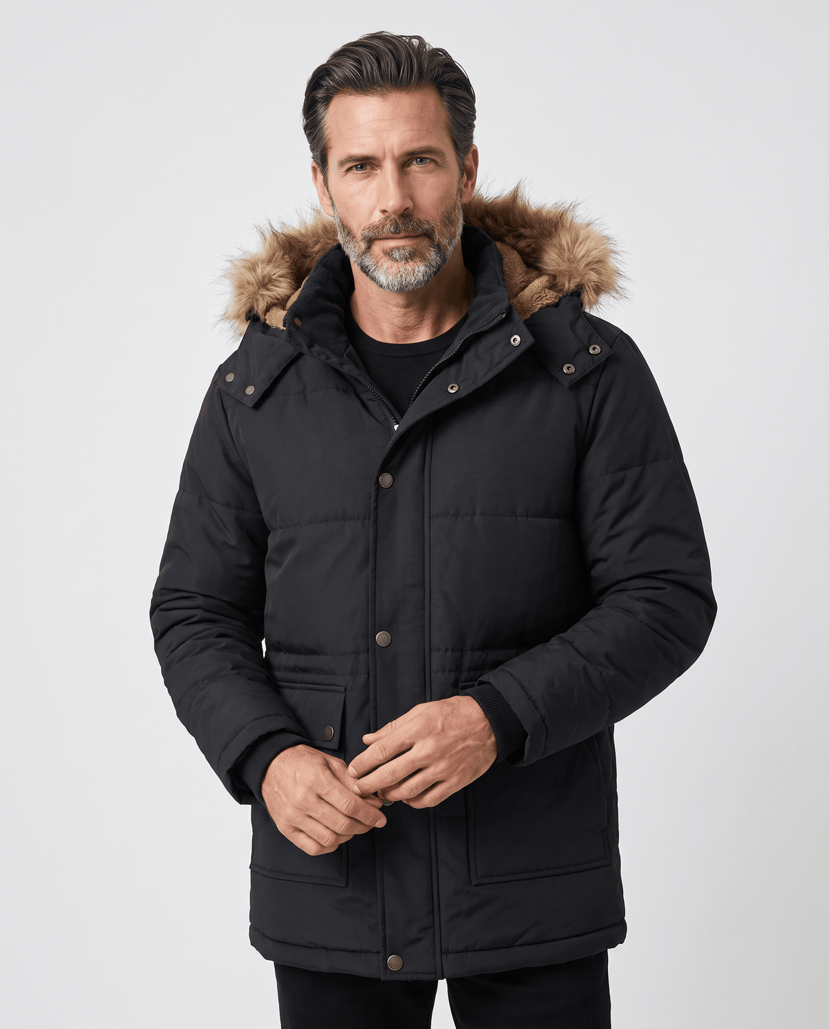 Man wearing black parka with fur-trim hood, hands together at the front