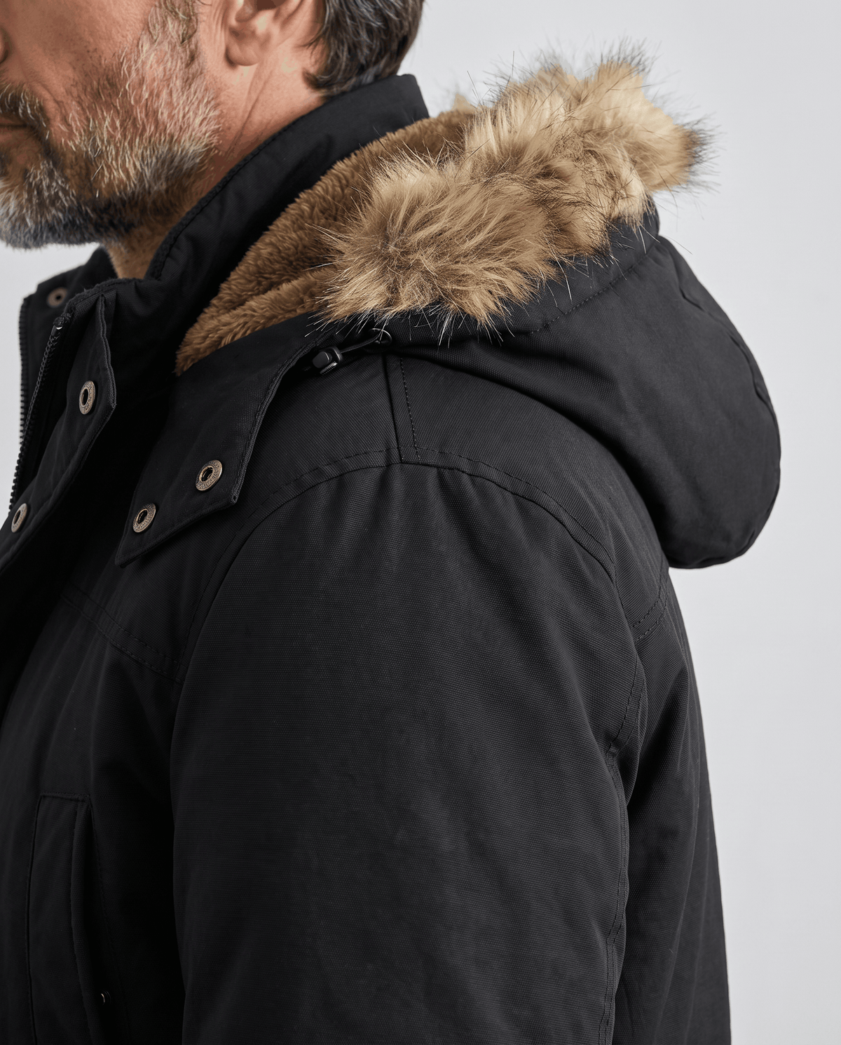 Side close-up of black parka hood with fur trim and snap collar detail