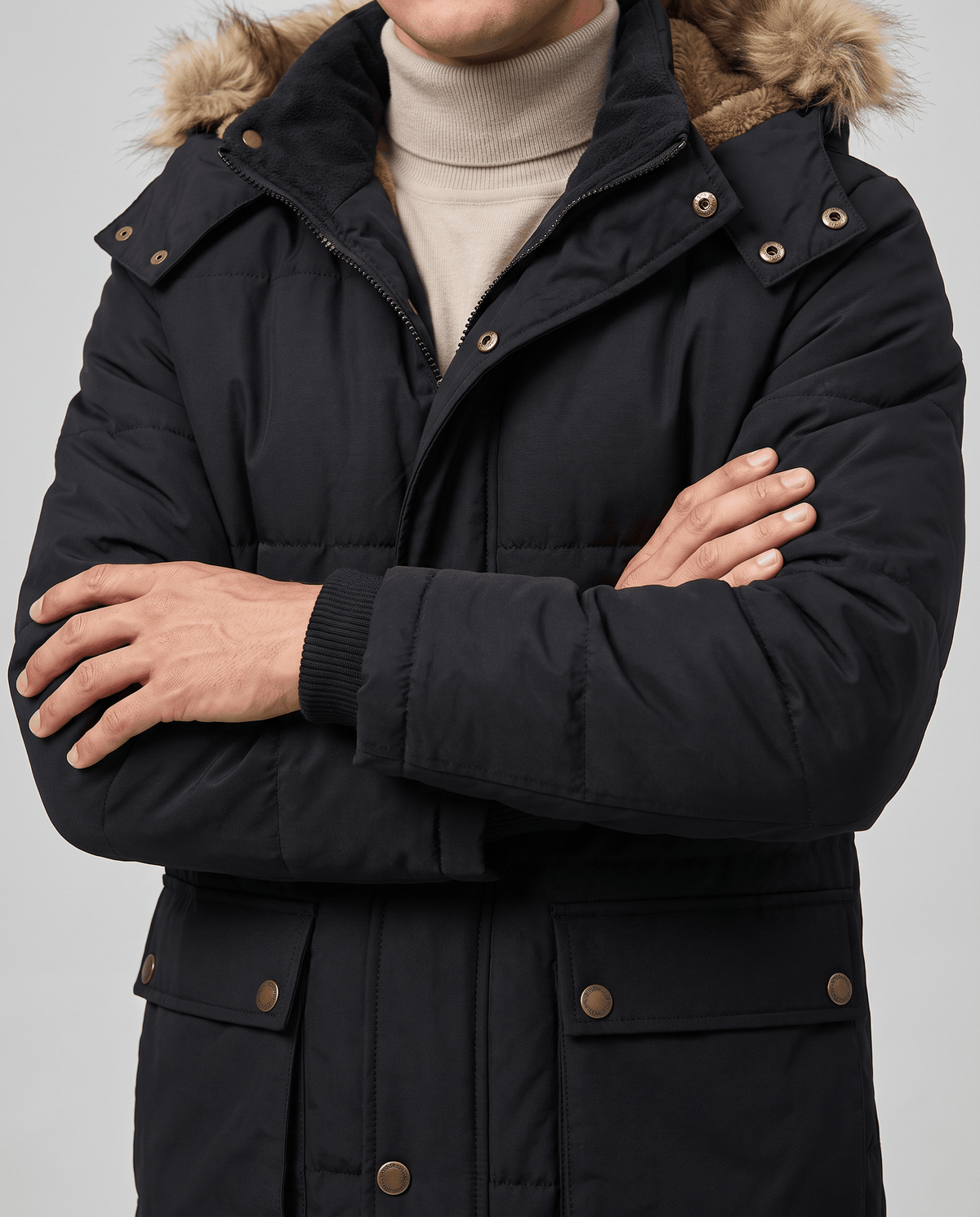 Man in black parka over cream turtleneck with arms crossed and fur trim at collar