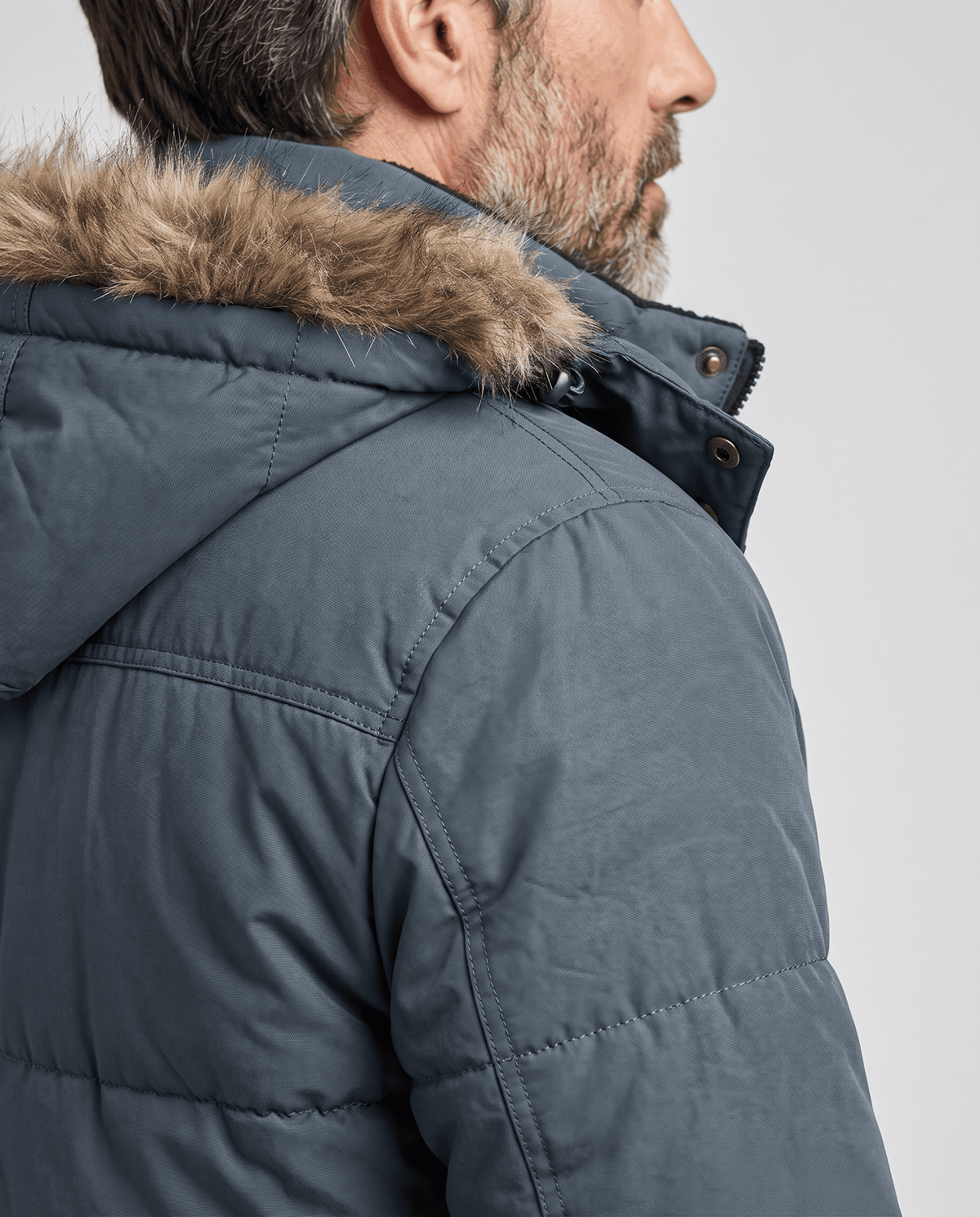 Side detail of dark blue padded sleeve and fur trim around the hood