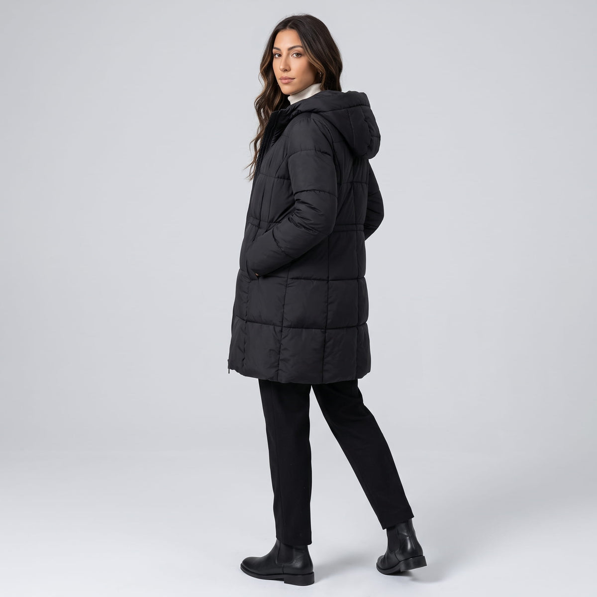 Model walking in black knee-length coat with black trousers and boots