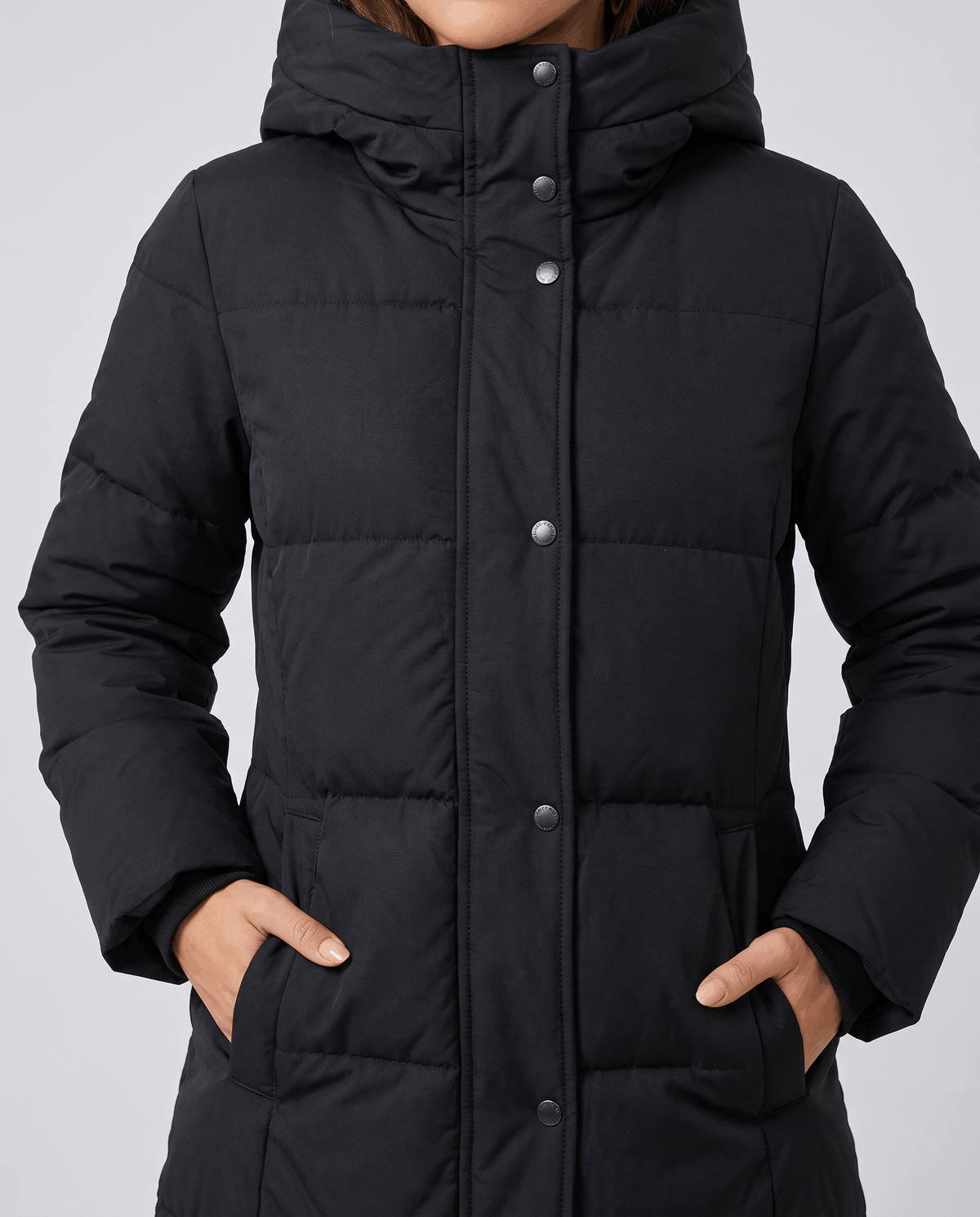 Close-up of black coat snap placket with hands in the side pockets