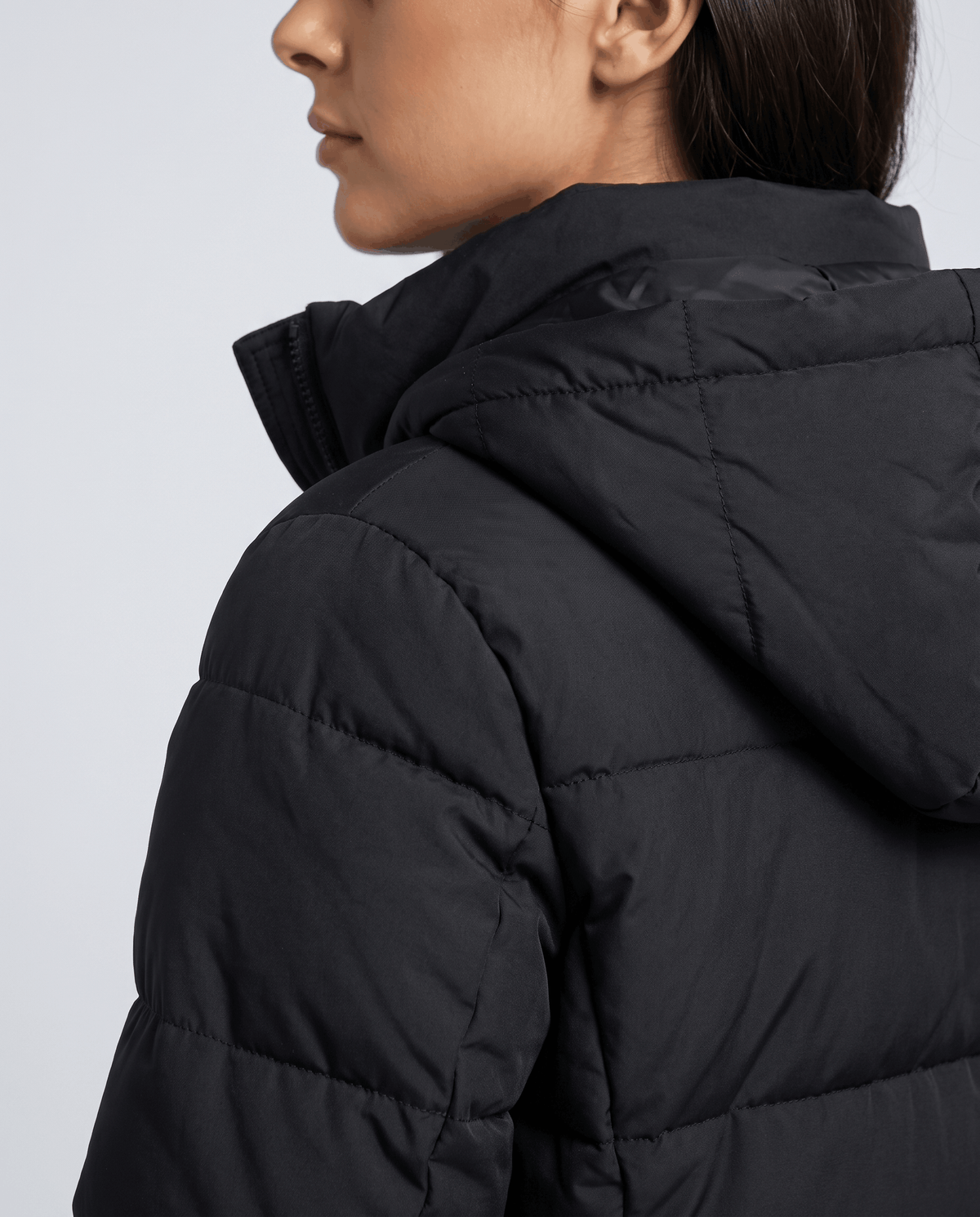 Side close-up of the black coat hood and quilted shoulder