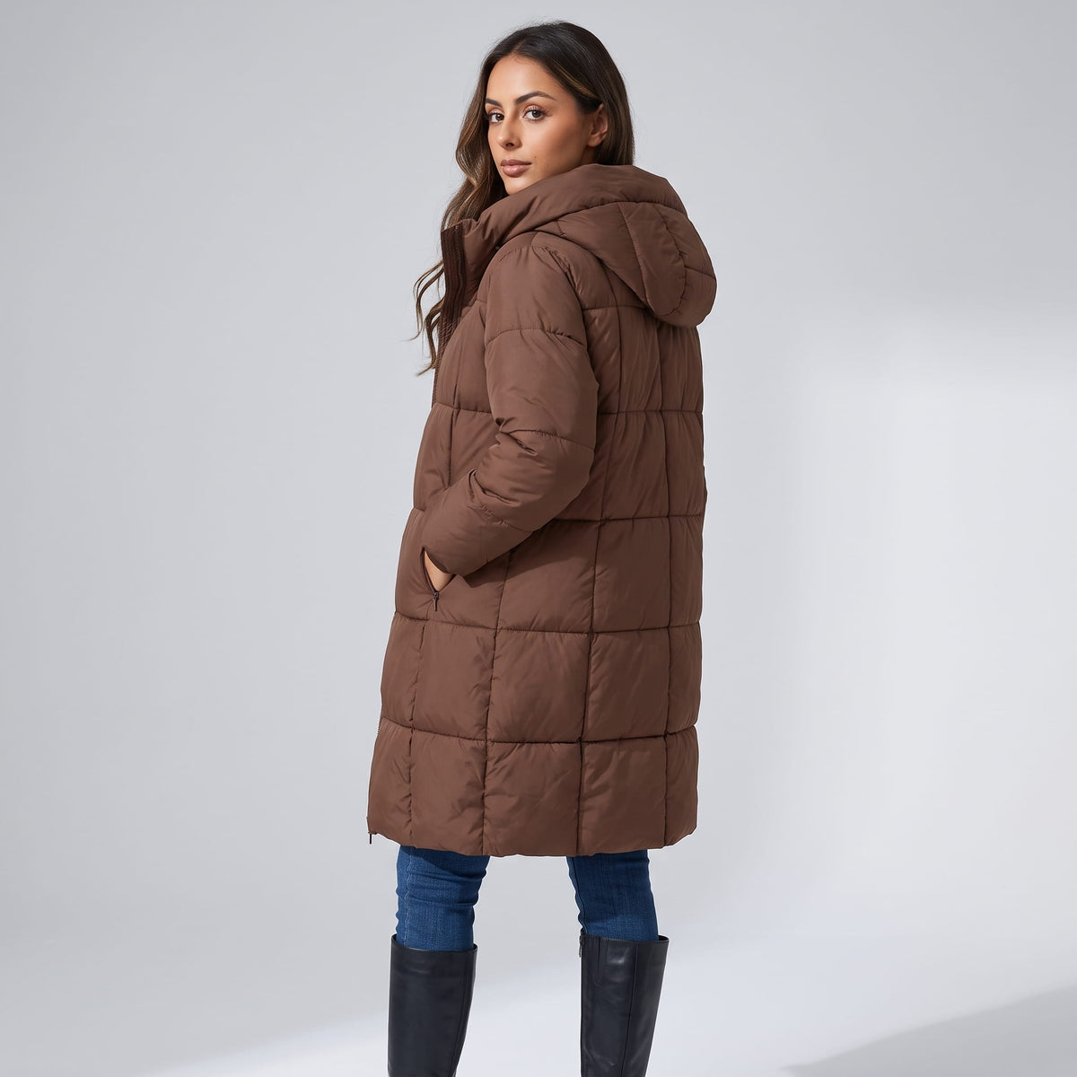 Side view of dark brown coat with the hood up and hands in pockets