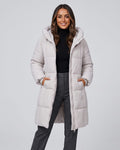 Woman in off-white knee-length quilted puffer coat over a black top and gray jeans