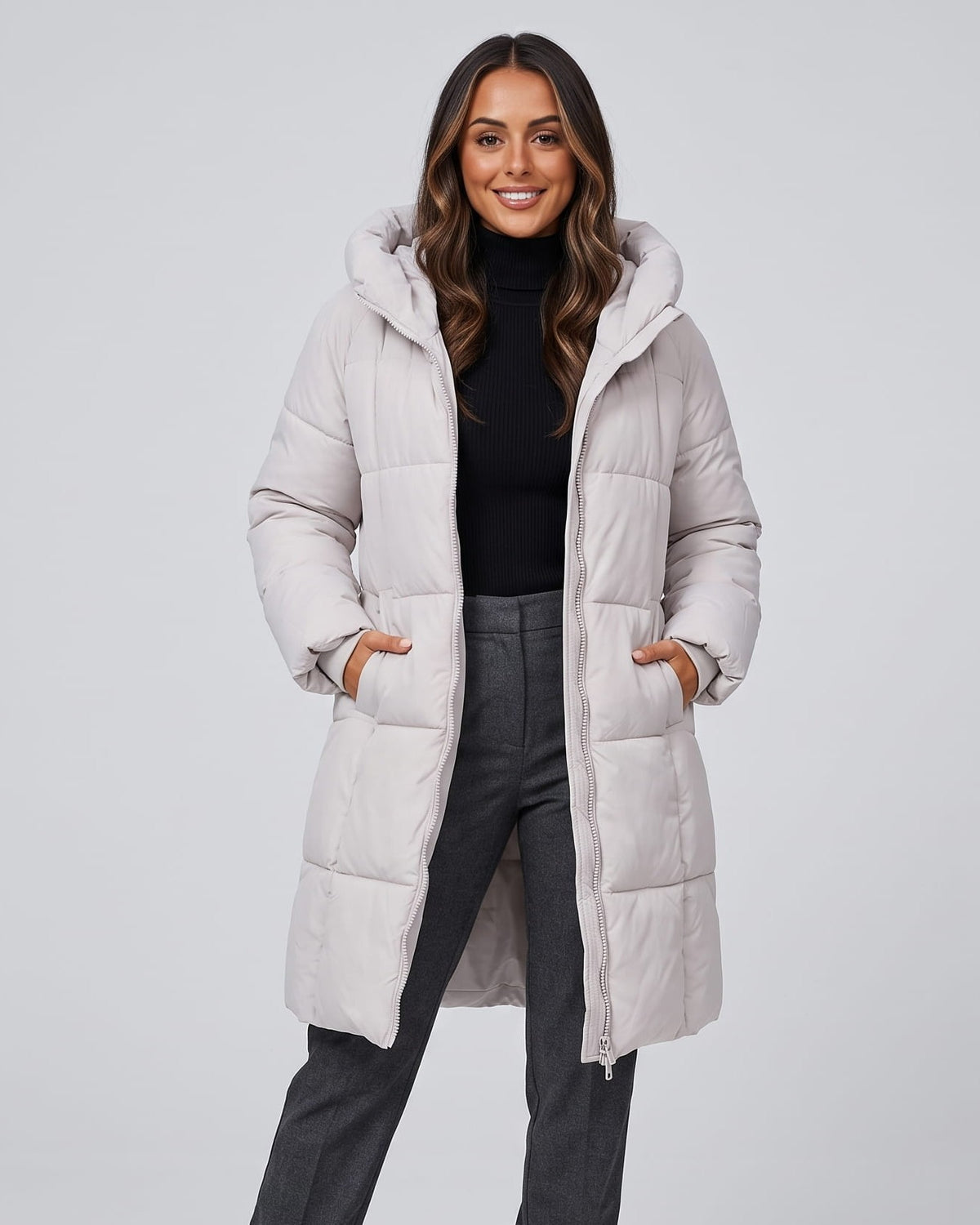 Woman in off-white knee-length quilted puffer coat over a black top and gray jeans