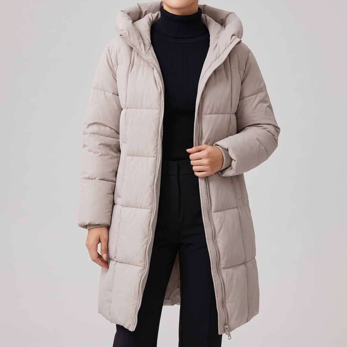 Off-white coat worn open over a black turtleneck and dark trousers