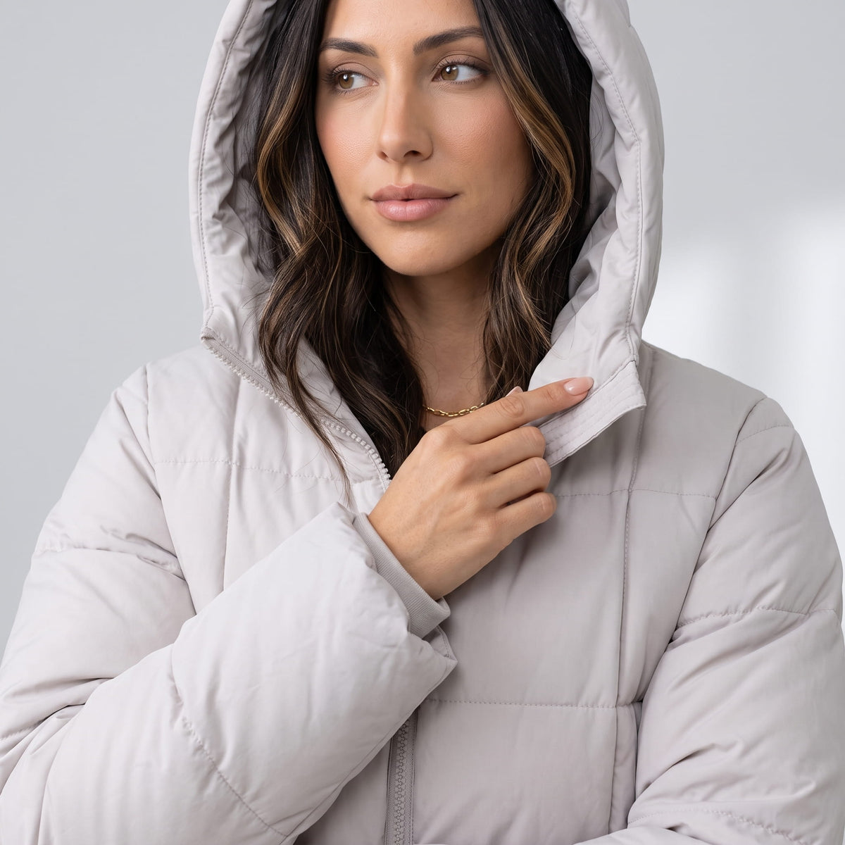 Model wearing the hood up on an off-white quilted puffer coat