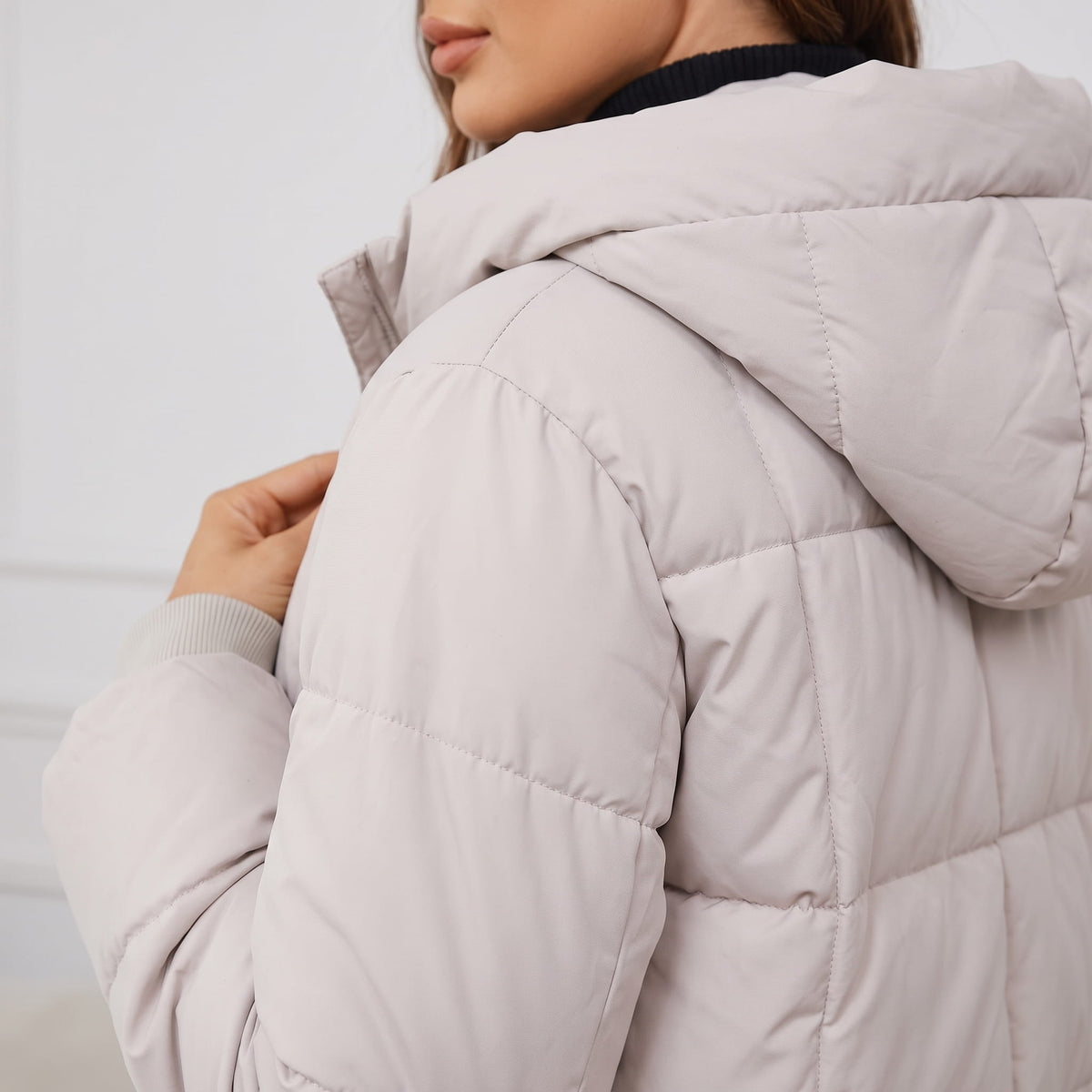 Side close-up of the off-white coat hood and quilted shoulder