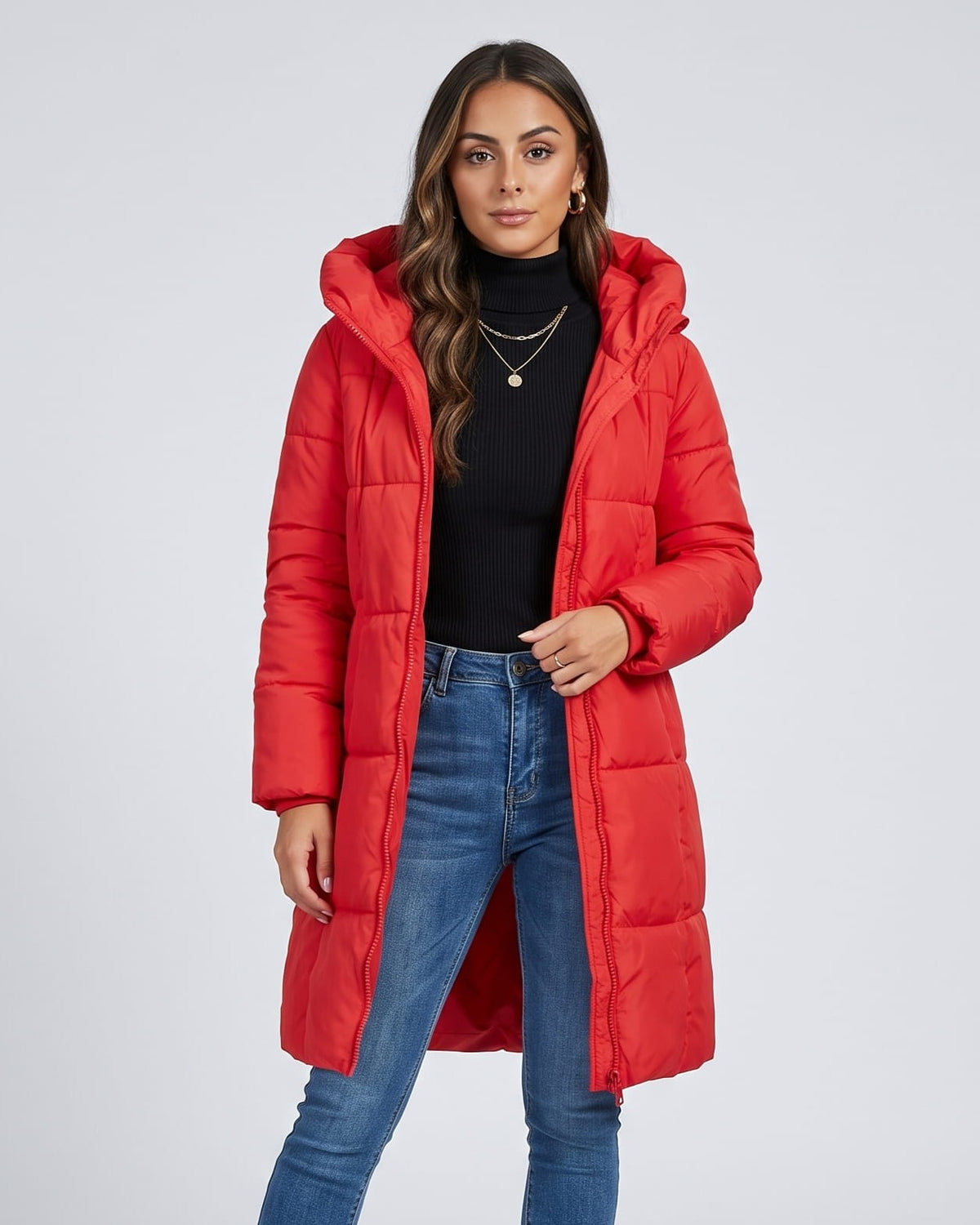 Woman in red knee-length puffer coat over a black top and blue jeans