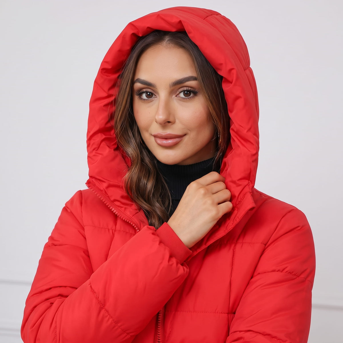 Model wearing the hood up on a red quilted puffer coat