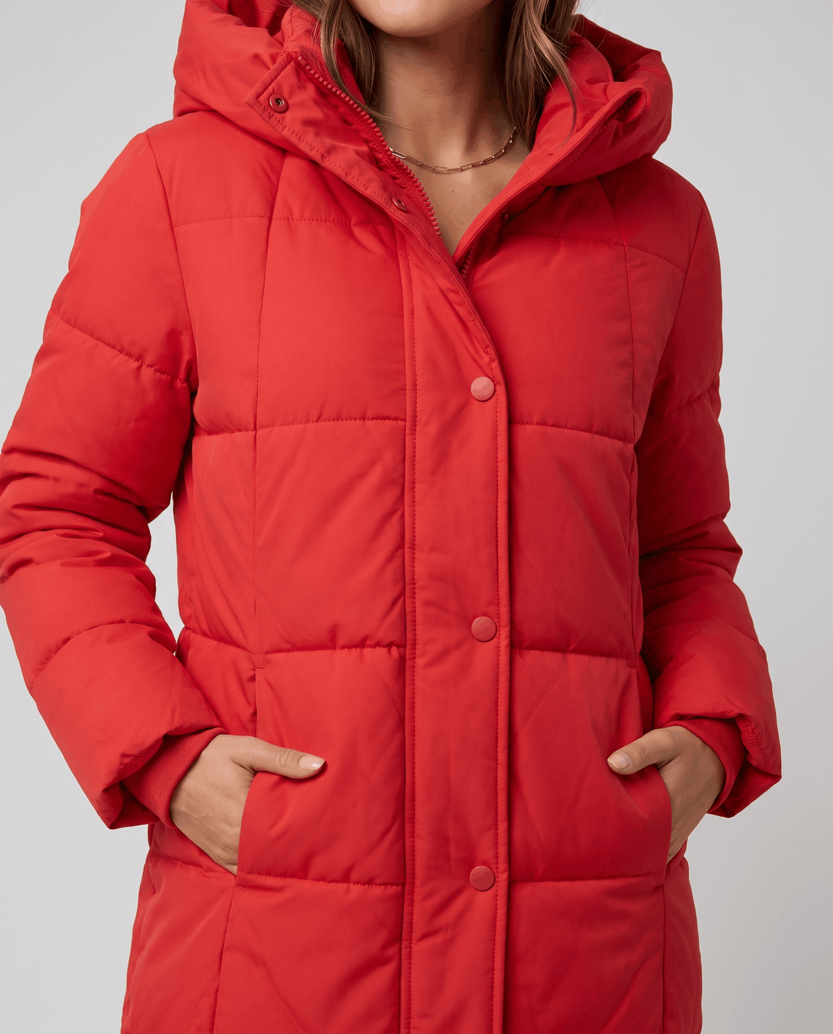 Close-up of red coat snap placket with hands in the side pockets