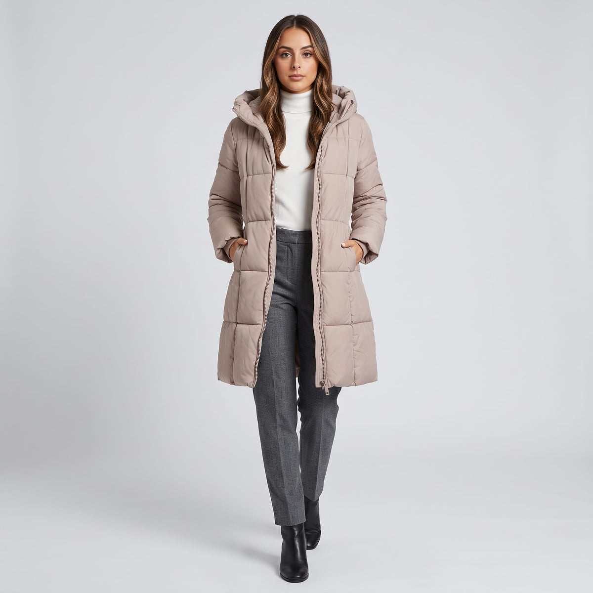 Model walking in taupe quilted coat with gray trousers and boots