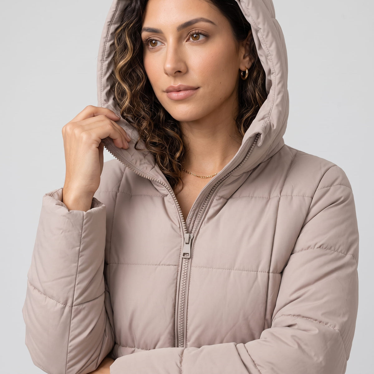 Close-up of taupe coat hood and front zip with hand at the collar