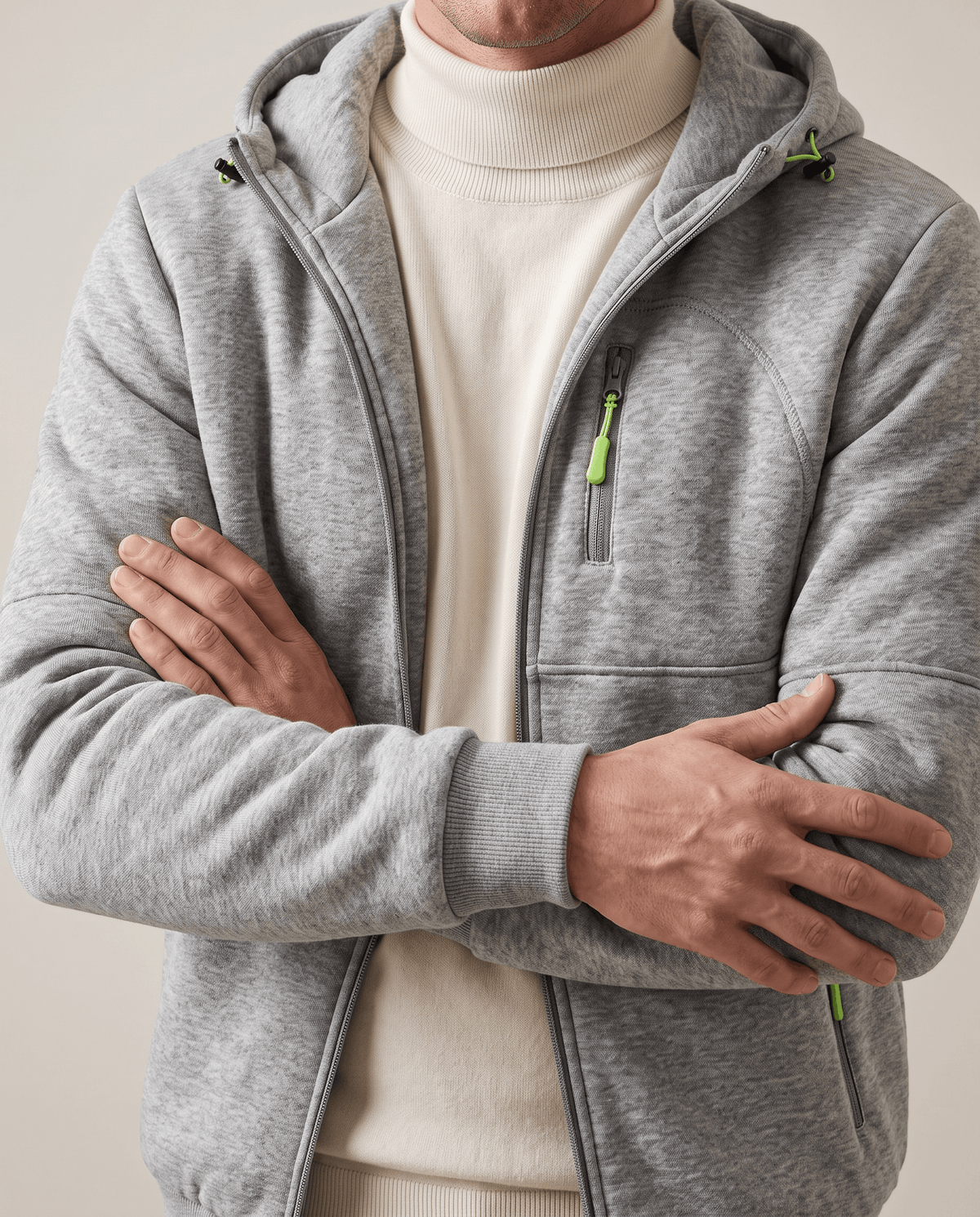 Heather gray hoodie worn open over a cream turtleneck, arms crossed