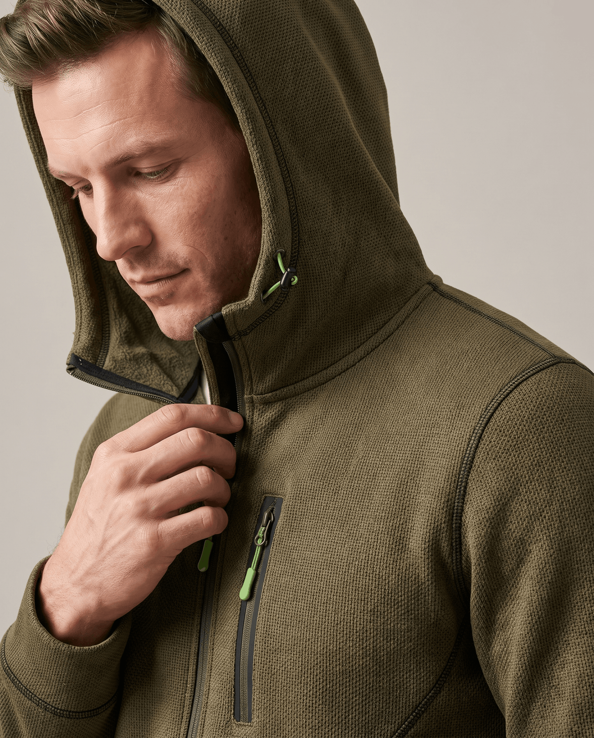Close-up of the olive hoodie worn with the drawstring hood up