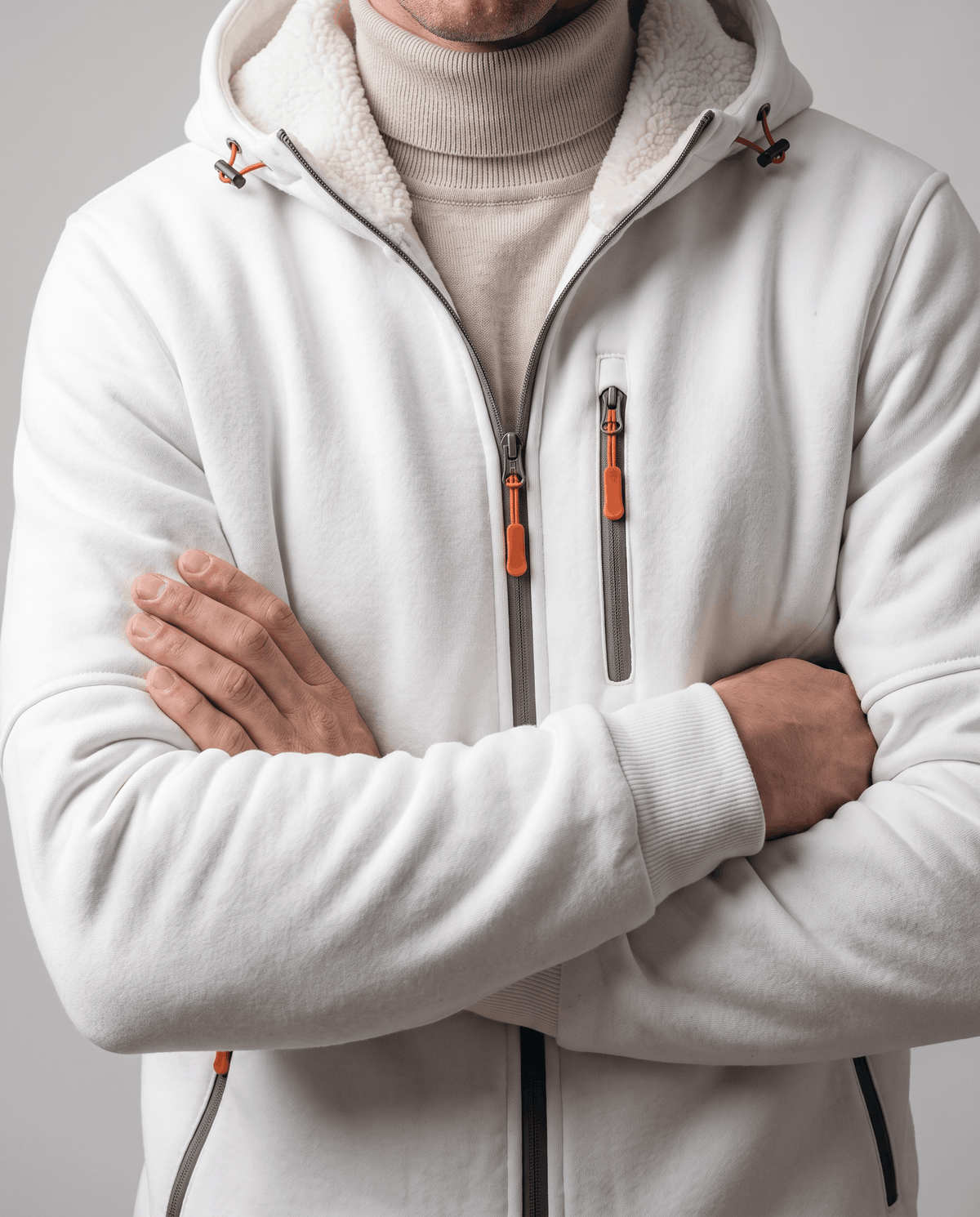 White hoodie worn over a cream turtleneck with arms crossed