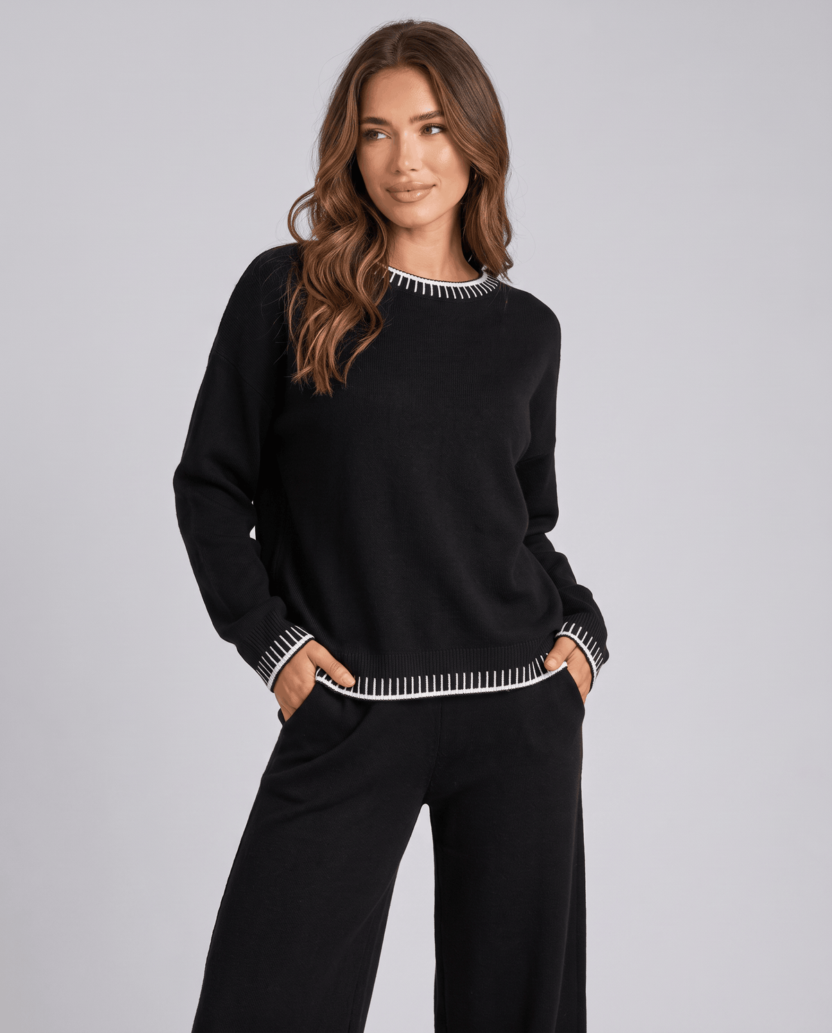 Black knit sweater with contrast trim at the hem, three-quarter front view