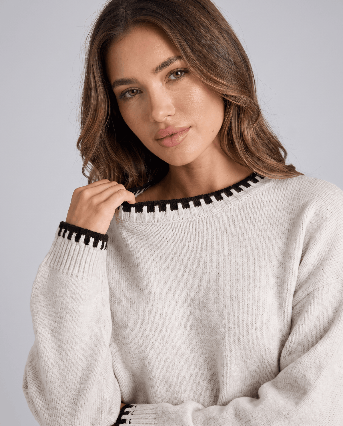 Close-up of the cream knit sweater with black contrast trim at the neckline
