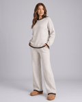 Woman wearing a cream knit lounge set with contrast trim sweater and wide-leg pants