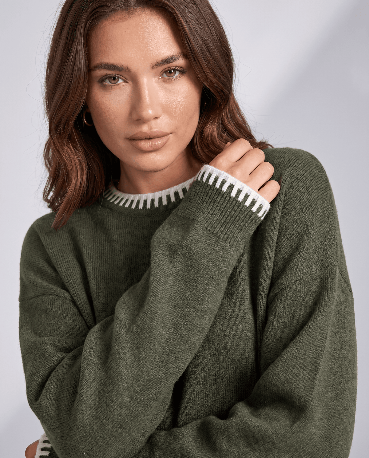 Close-up of the dark green knit sweater with contrast trim at the cuff