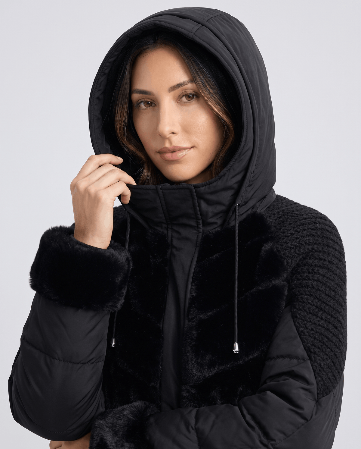 Model wearing the drawstring hood up on a black plush-trimmed jacket