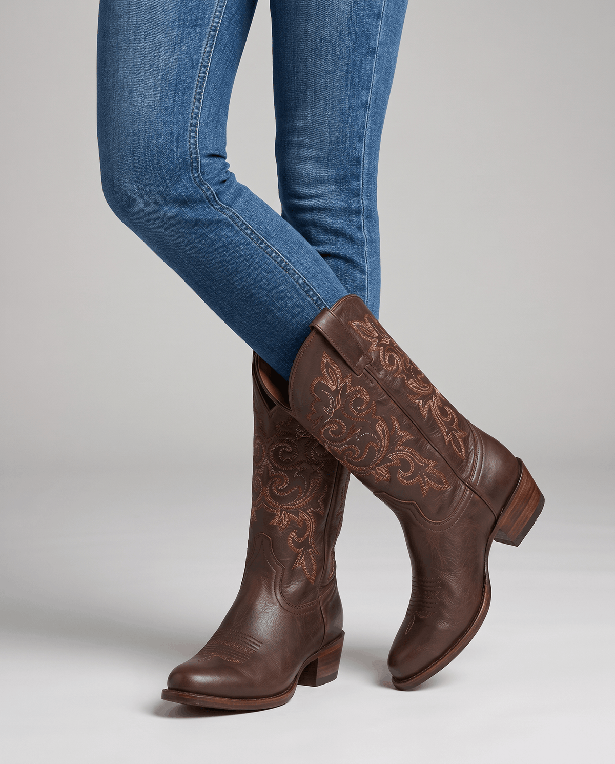 Studio shot of blue jeans worn with tall brown embroidered boots and stacked heels