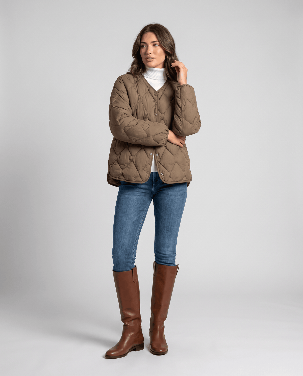 Full-length view of model in brown quilted jacket, jeans and tall brown boots
