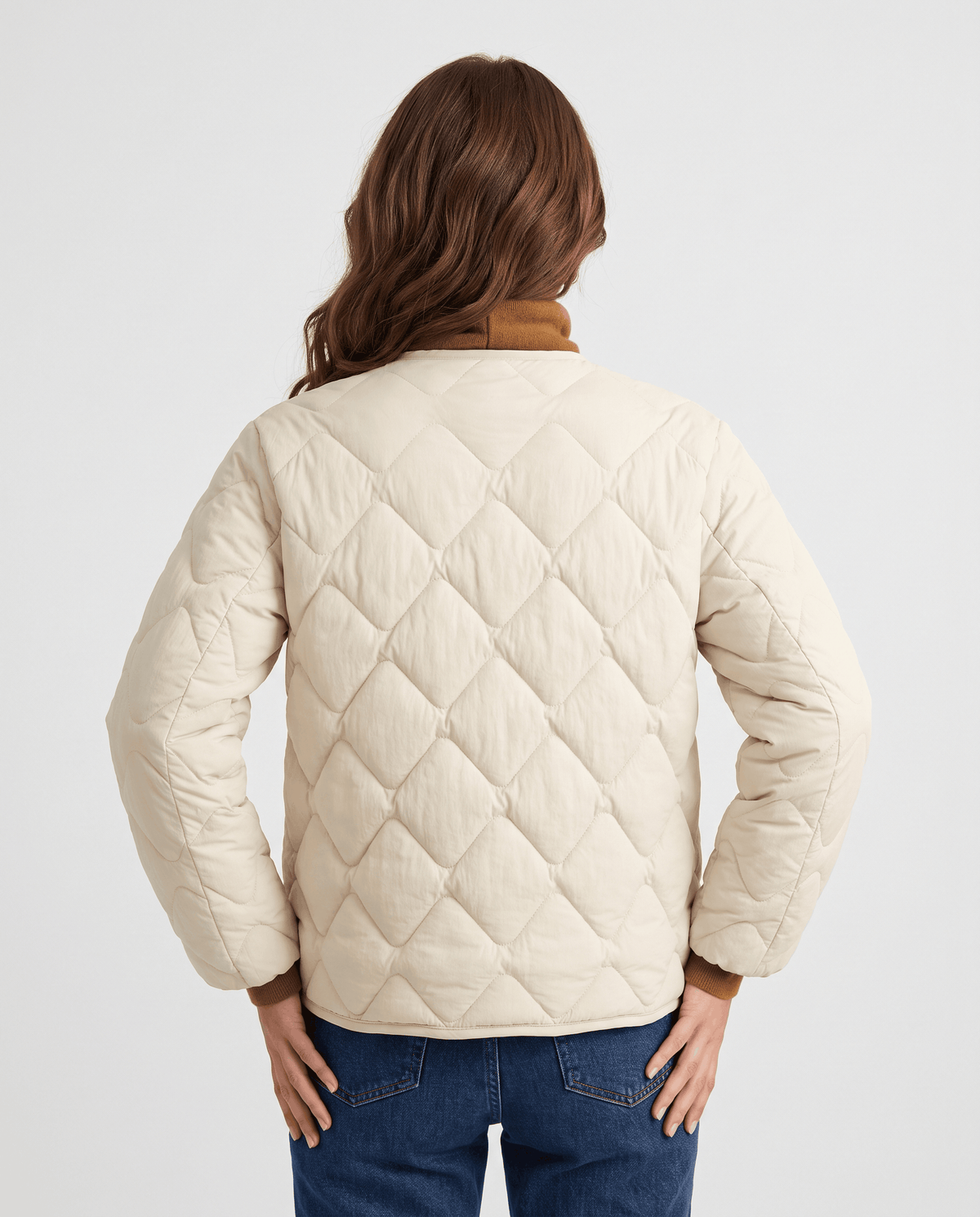 Back view of cream diamond quilted jacket worn with brown turtleneck and jeans