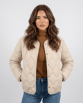 Woman wearing lightweight duck down jacket in cream with diamond quilting and snap front
