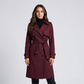 Woman in burgundy long belted trench coat over a black turtleneck, front view