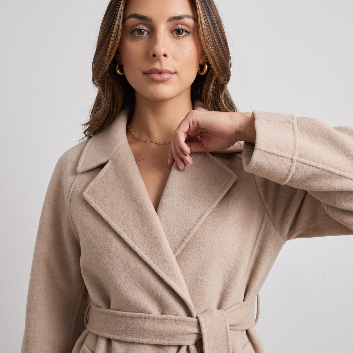 Close-up of beige coat notched lapel with the tie belt knotted at the waist