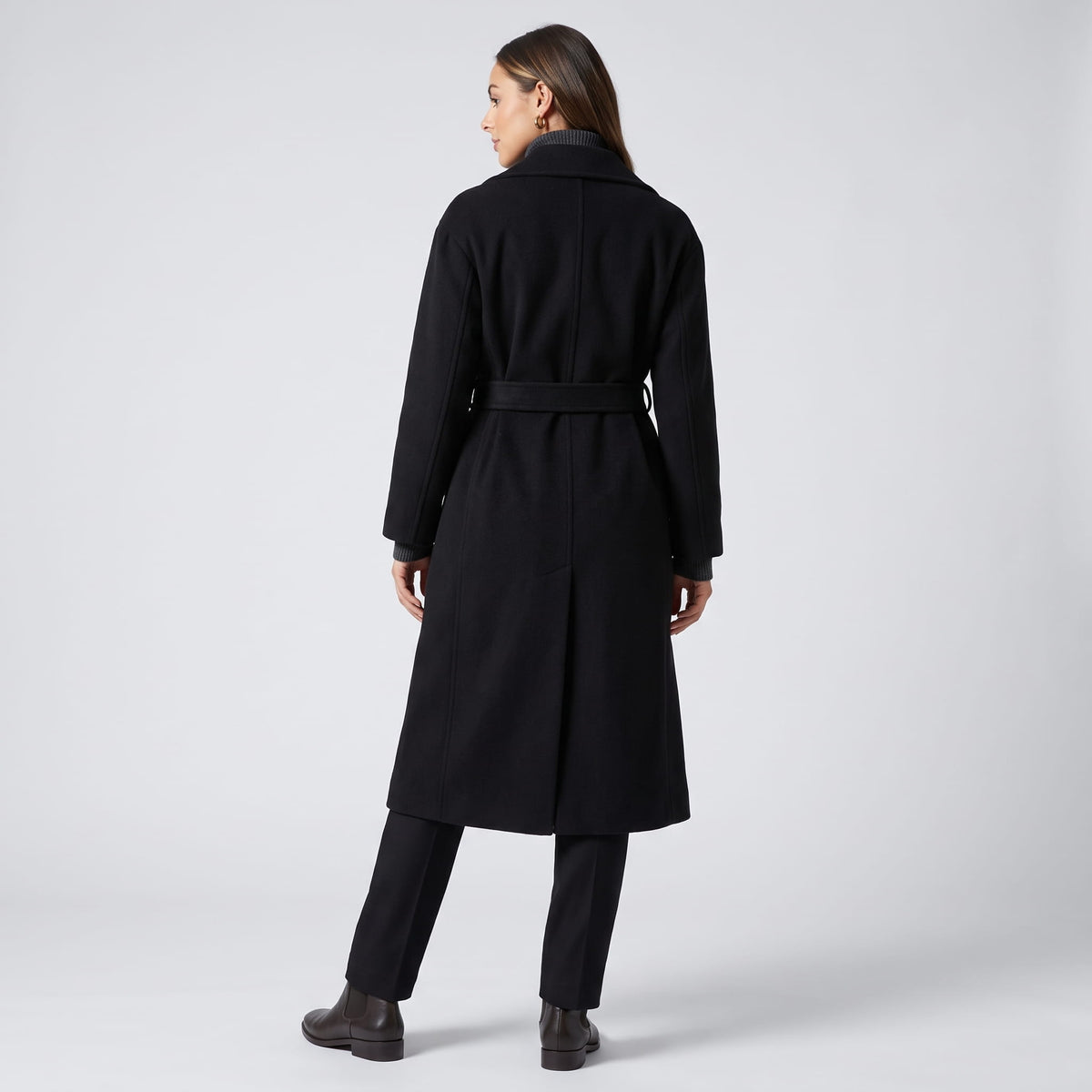Back view of black coat with belted waist and black ankle boots