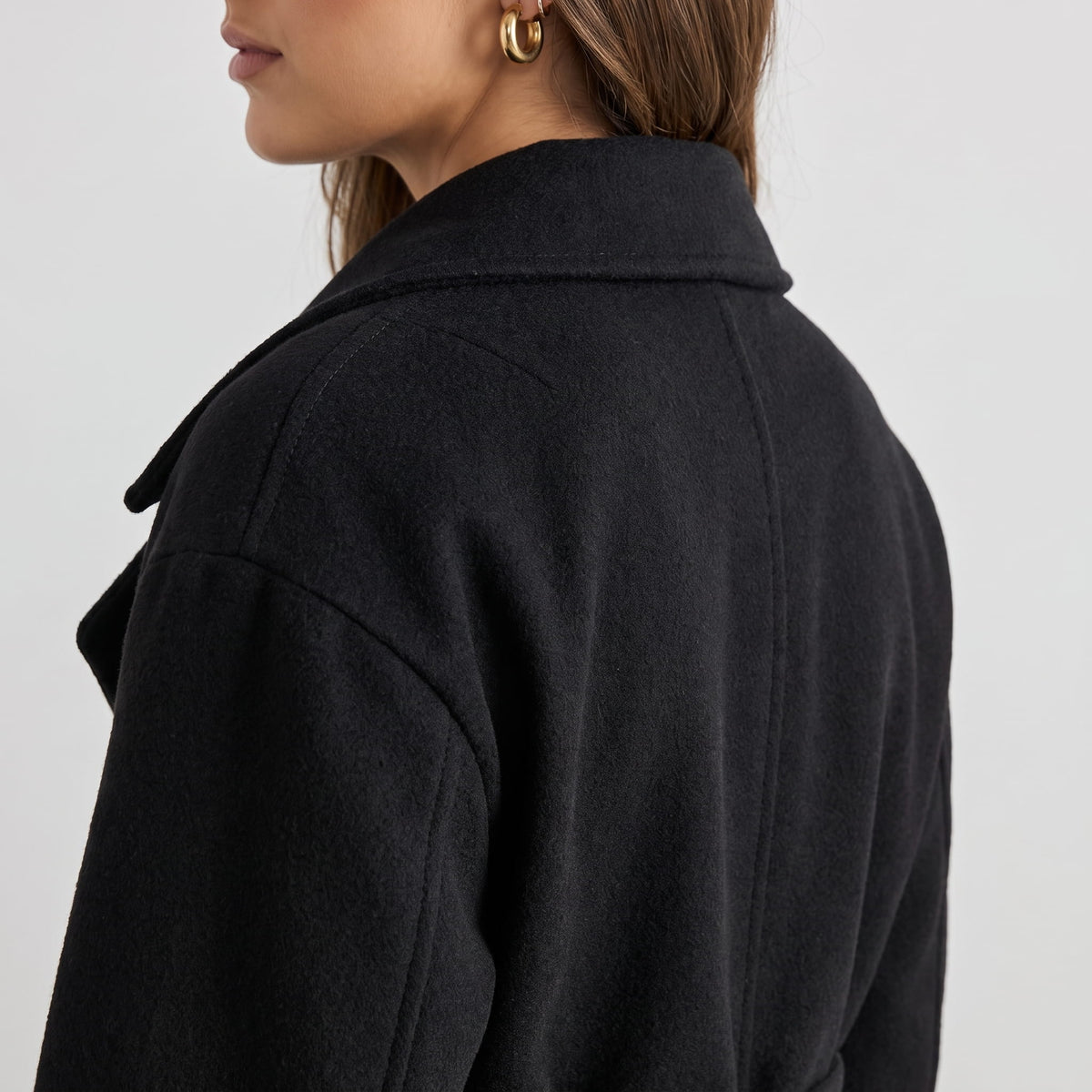 Rear shoulder detail of black coat showing the collar and dropped shoulder