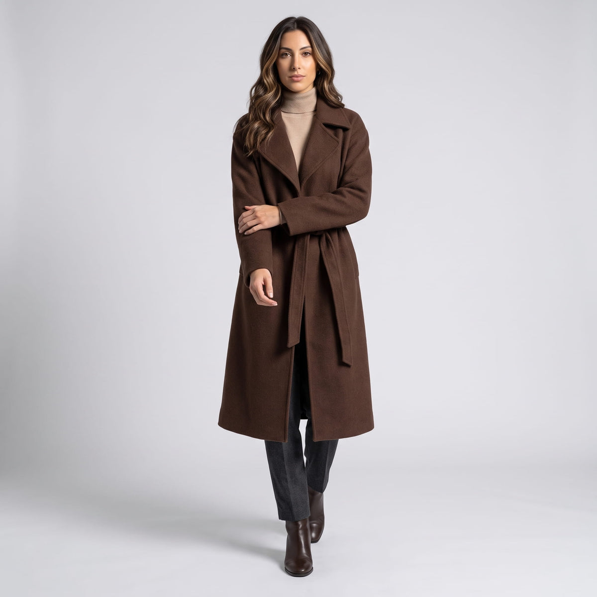 Model walking in brown coat belted at the waist with dark trousers and boots