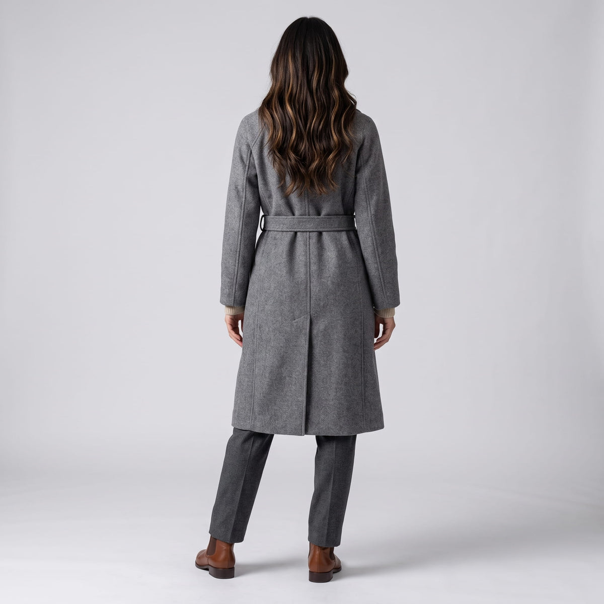 Back view of gray coat with belted waist and brown ankle boots