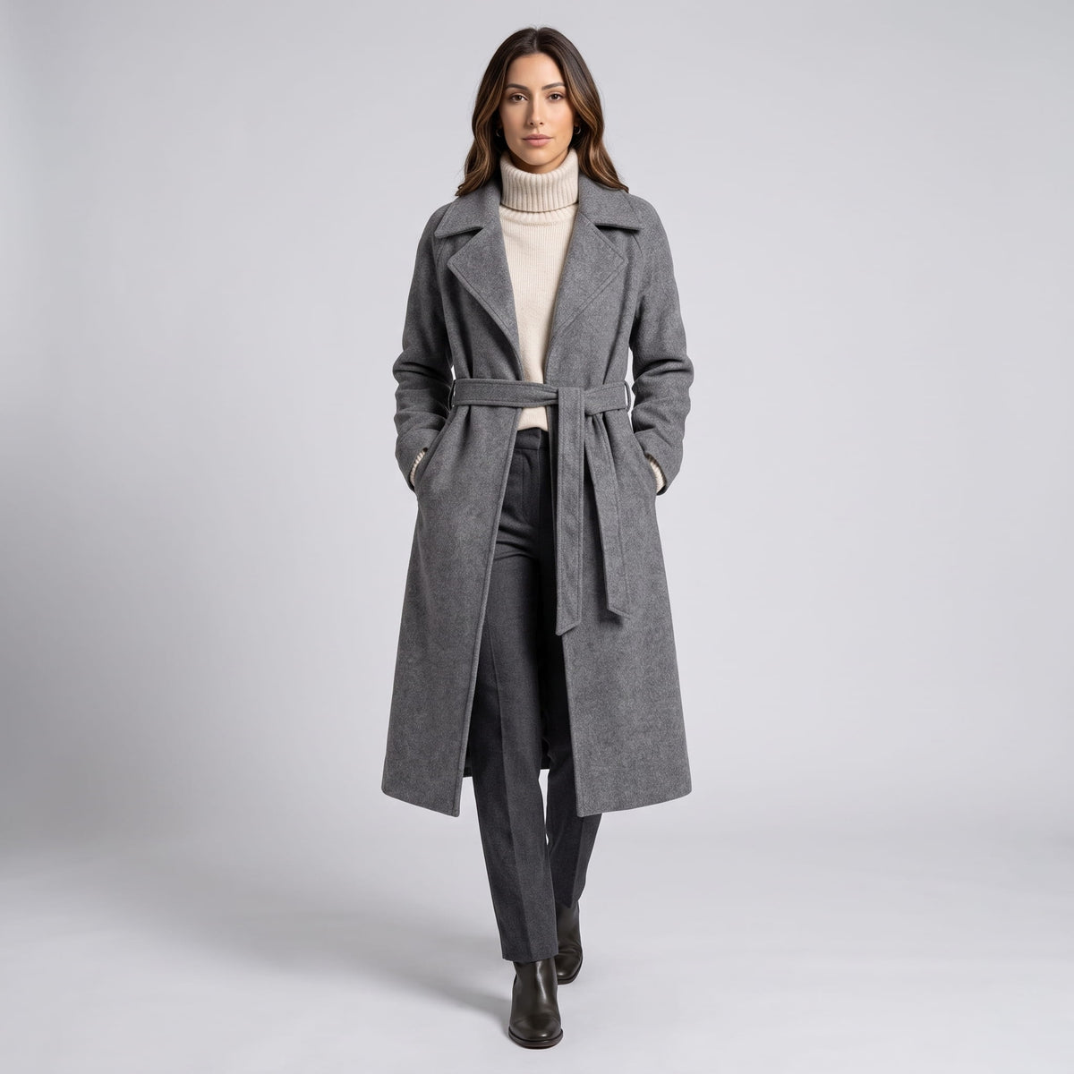 Model walking in gray coat belted at the waist with dark trousers