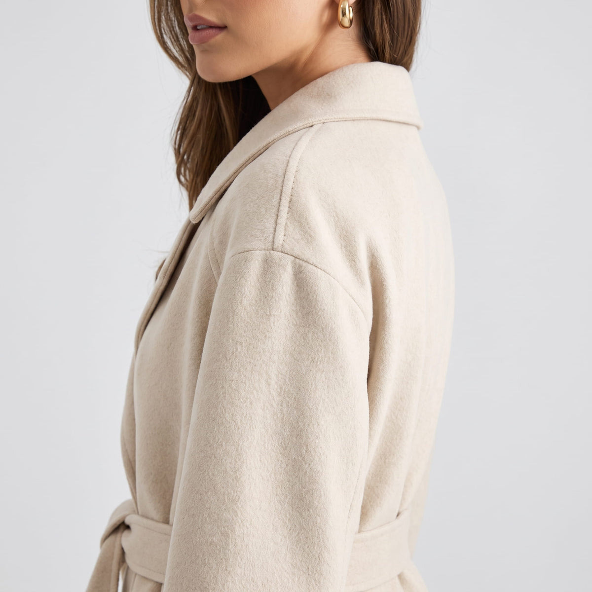 Side shoulder detail of off-white coat showing the dropped shoulder seam