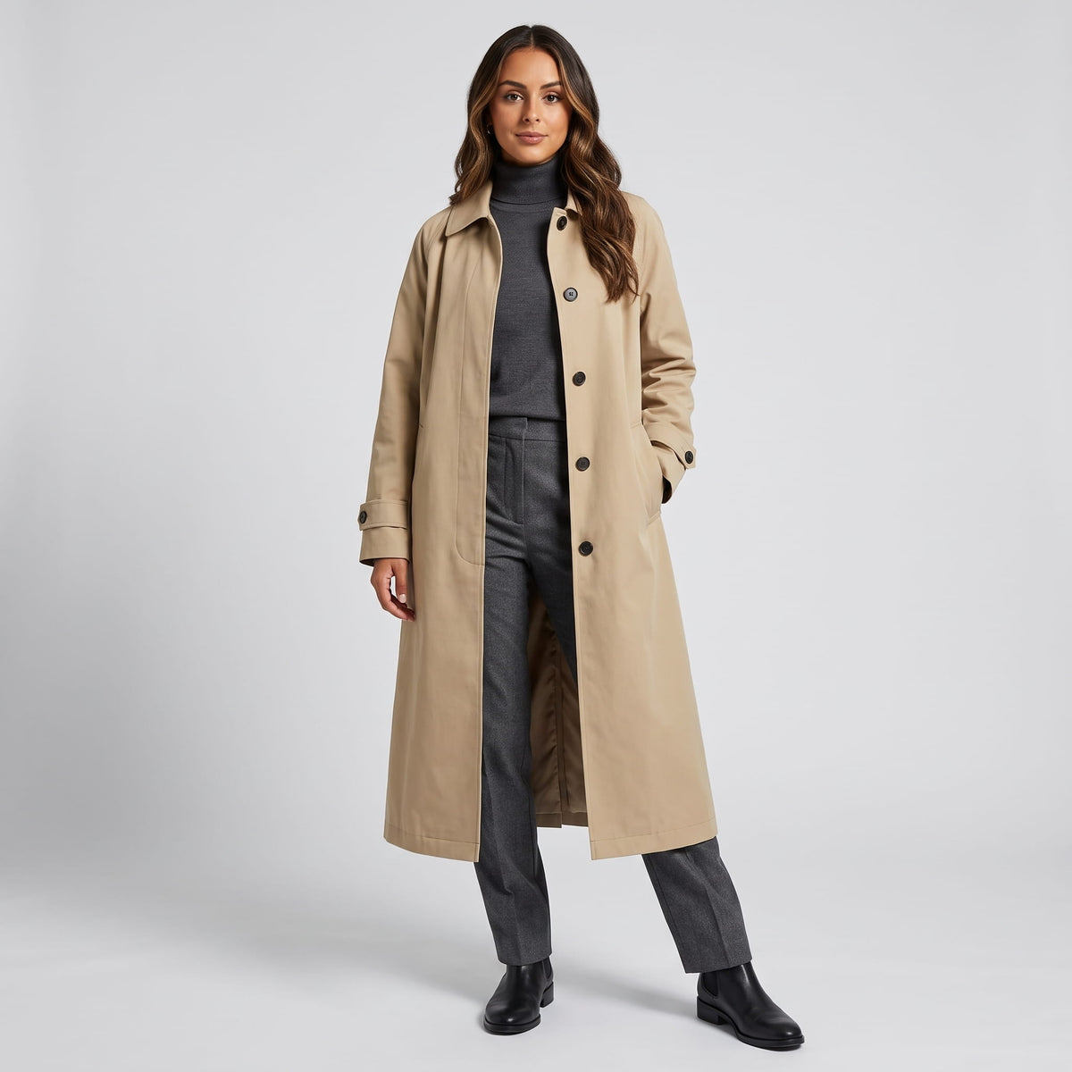 Woman in khaki long cotton trench coat over a charcoal turtleneck and gray trousers