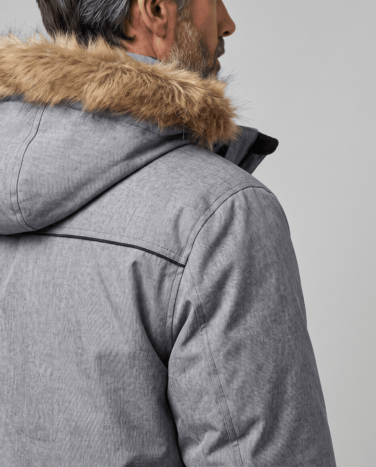 Rear close-up of gray parka hood with fur trim and shoulder seam detail