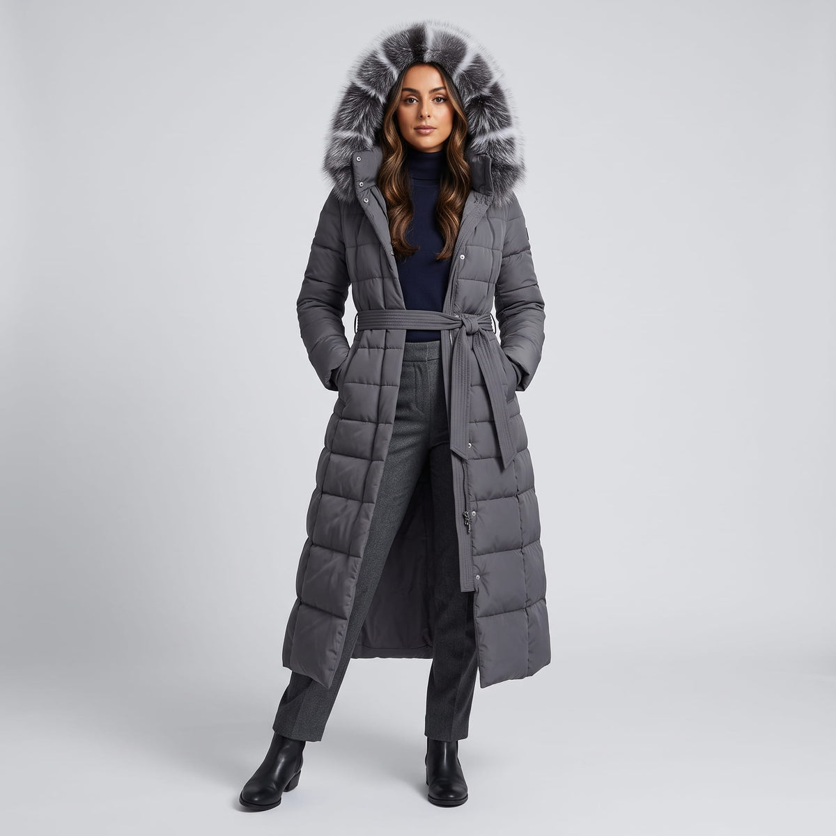 Woman in gray long hooded puffer coat with plush trim and tie belt