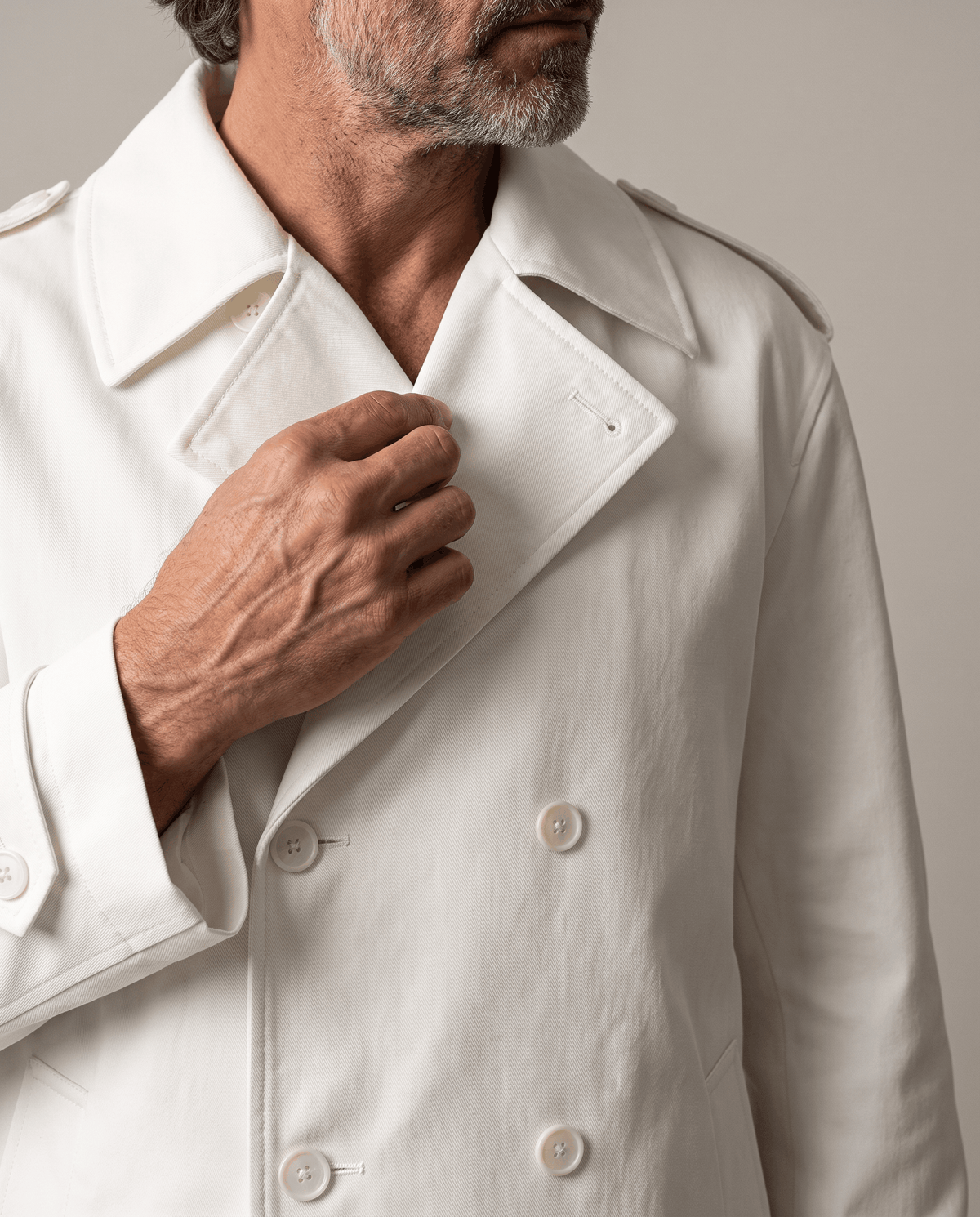 Close-up of white trench coat notch lapel, double-breasted buttons and epaulet