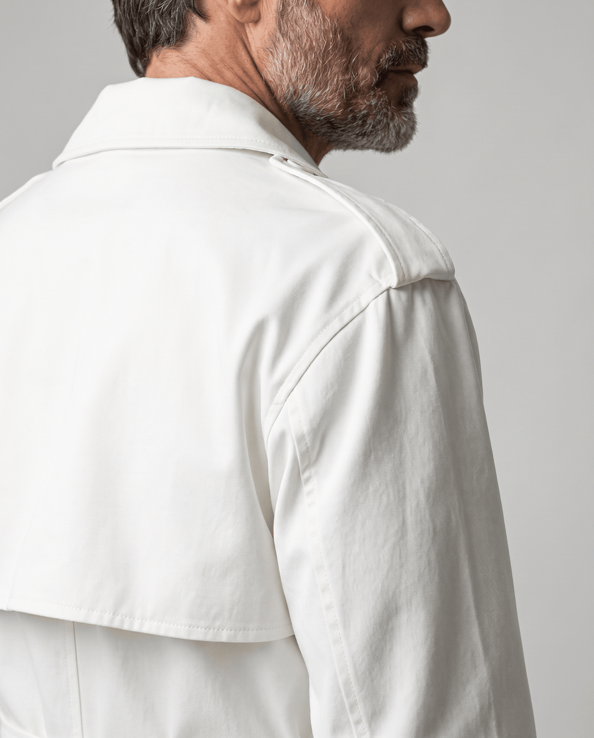 Side-back close-up of white trench coat storm yoke and shoulder epaulet
