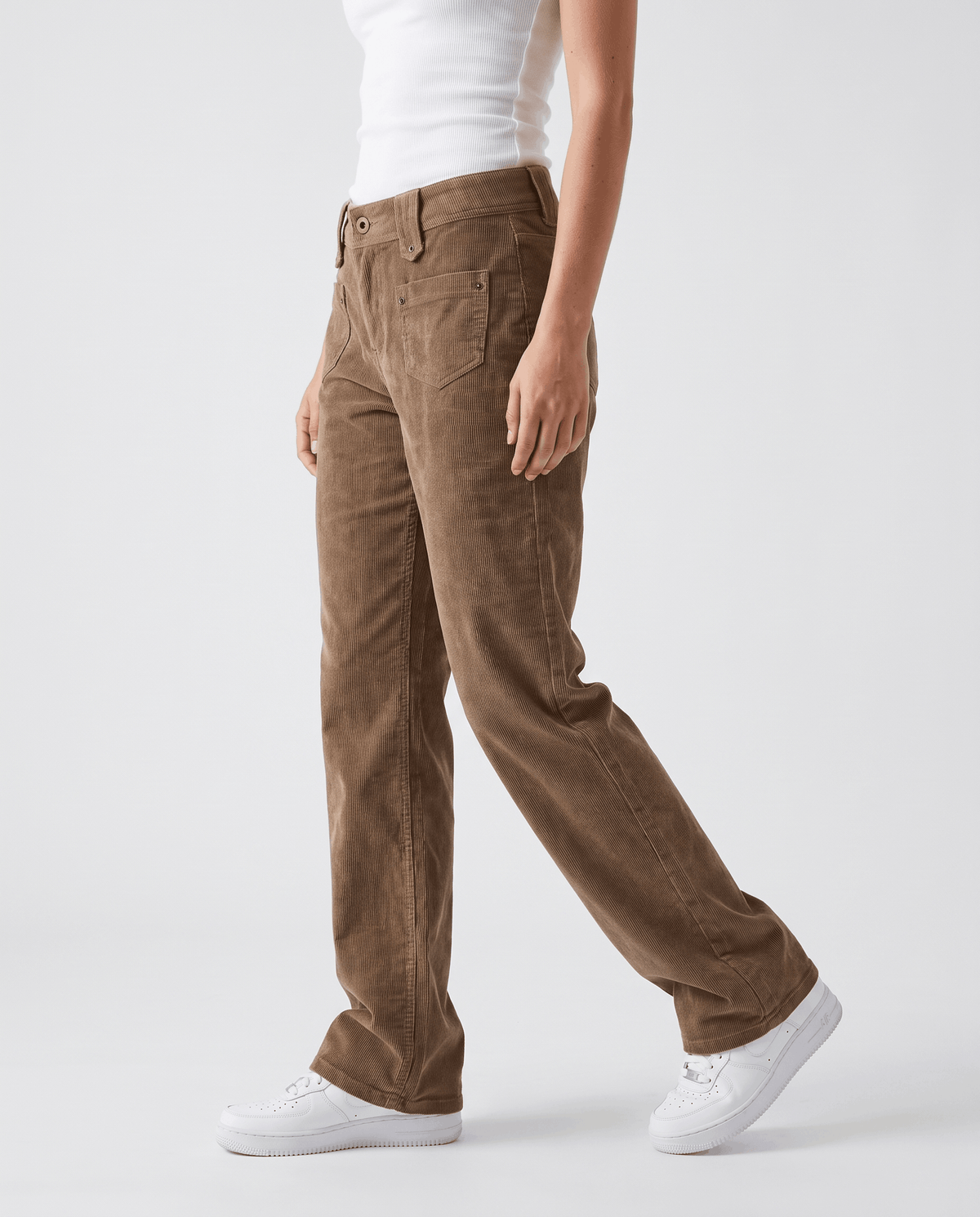 Side view mid-stride of taupe ribbed trousers showing the gently flared full-length leg