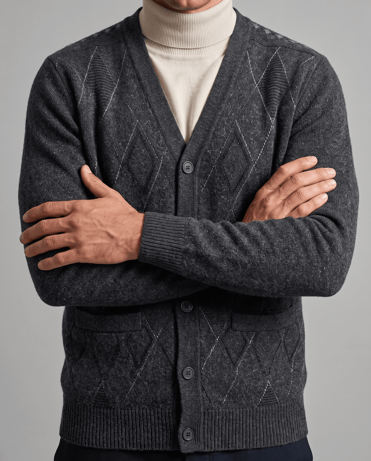 Arms crossed in a dark gray cardigan over a cream turtleneck showing patch pockets